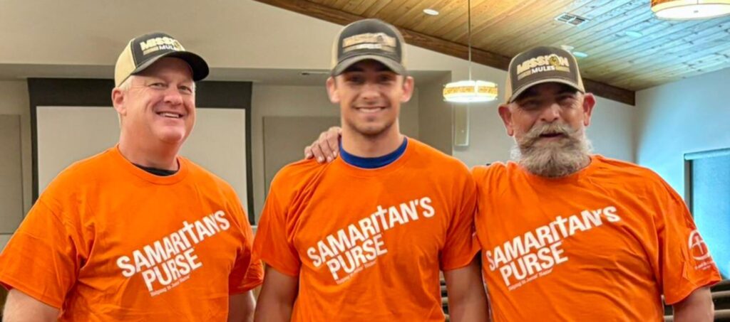 3 men wearing ball caps with words Mission Mules and orange tee shirts with words Samaritan's Purse